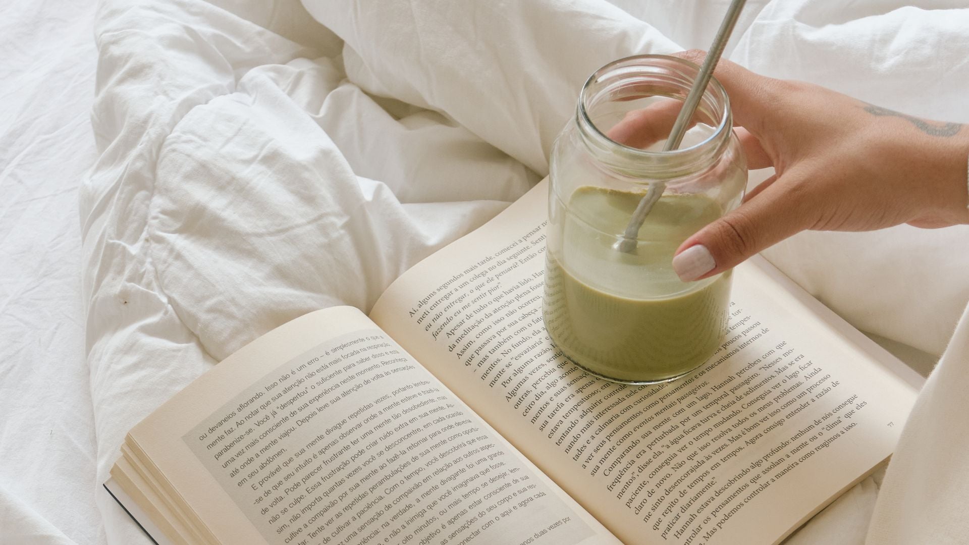 woman sitting on bed relaxing with a coffee and reading book